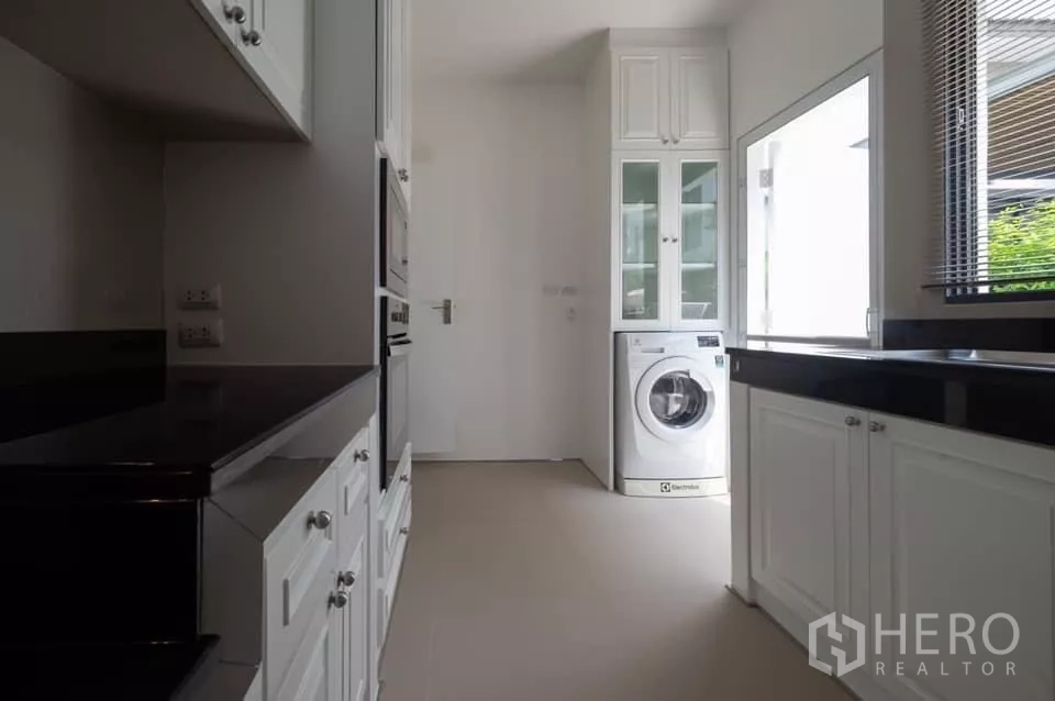 Detached House for rent in Prawet, Bangkok - Utility room with white cabinetry, black countertops and washing machine.