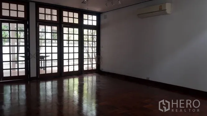 Detached House for rent in Yan Nawa, Bangkok - Spacious living room with parquet wood floor and full-height French doors opening to the patio.
