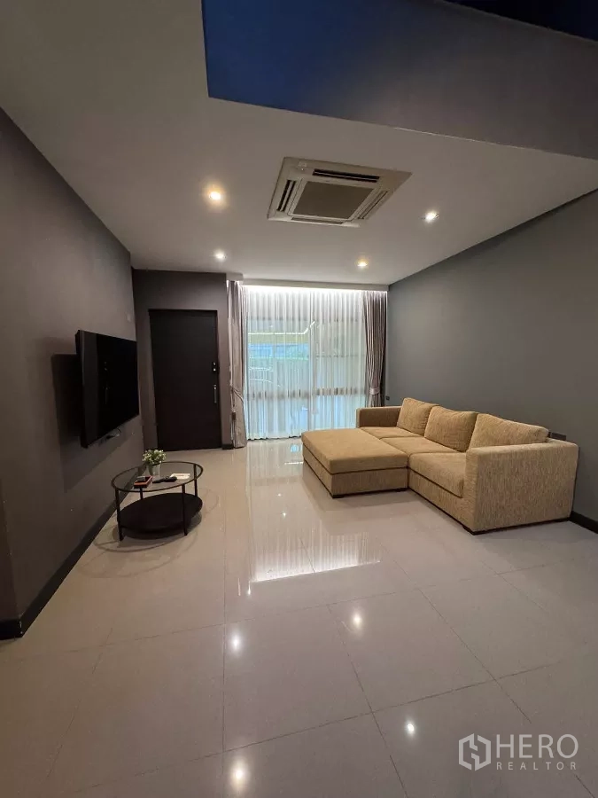 Townhouse for rent or sale in Lat Phrao, Bangkok - Living area facing sheer curtained windows allowing natural light.