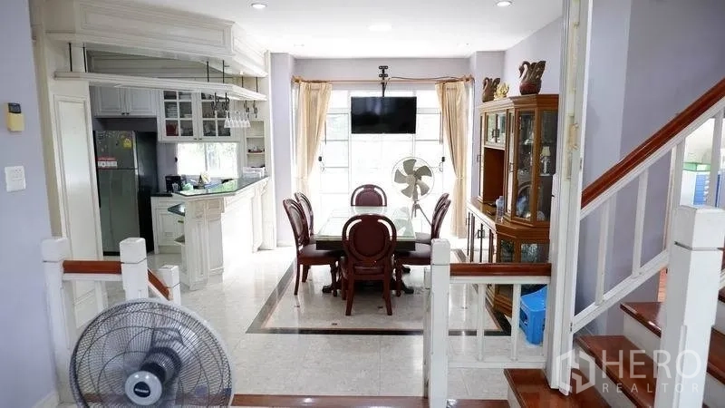 独立式住宅 出租在Prawet, Bangkok - 从楼梯望向餐厅与厨房，带内置展示柜与瓷砖地面。