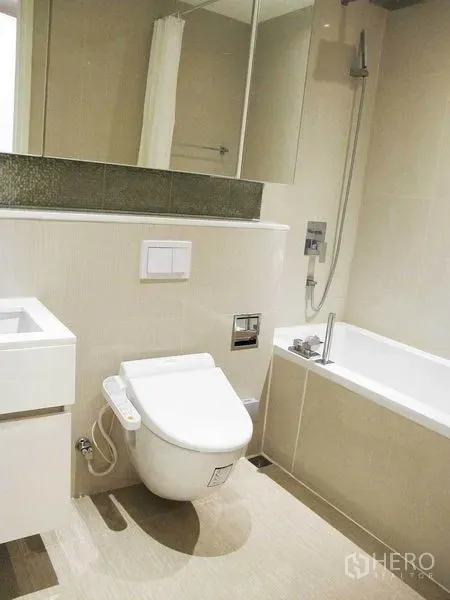 Condominium for rent in Watthana, Bangkok - Modern bathroom with bathtub, rain shower, bidet toilet and mirrored vanity.