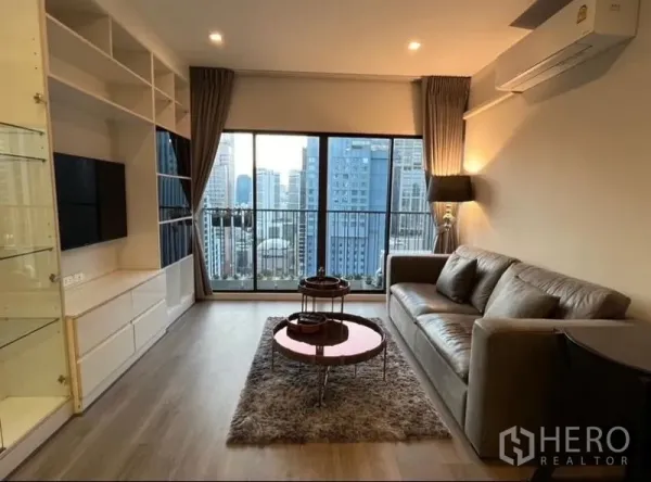 Condominium for rent in Bangkok - Living area with built-in media wall, shag rug and skyline view through sliding glass doors.