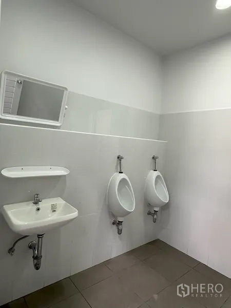 Factory for rent in Khlong Luang, Pathum Thani - Restroom with sink and urinals in a bright tiled finish.