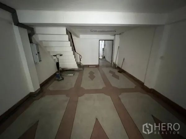 Shophouse for rent in Phra Khanong, Bangkok - Deep front room with patterned flooring, side staircase and doorway connecting to the back service area.