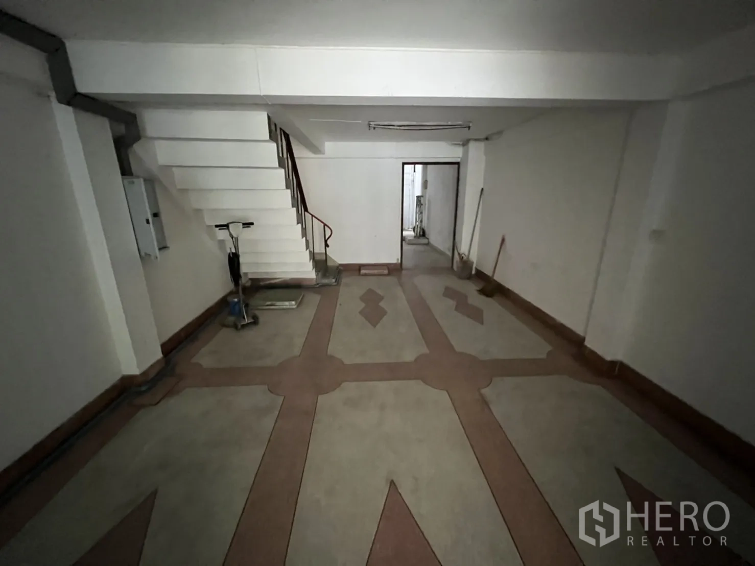 Shophouse for rent in Phra Khanong, Bangkok - Deep front room with patterned flooring, side staircase and doorway connecting to the back service area.