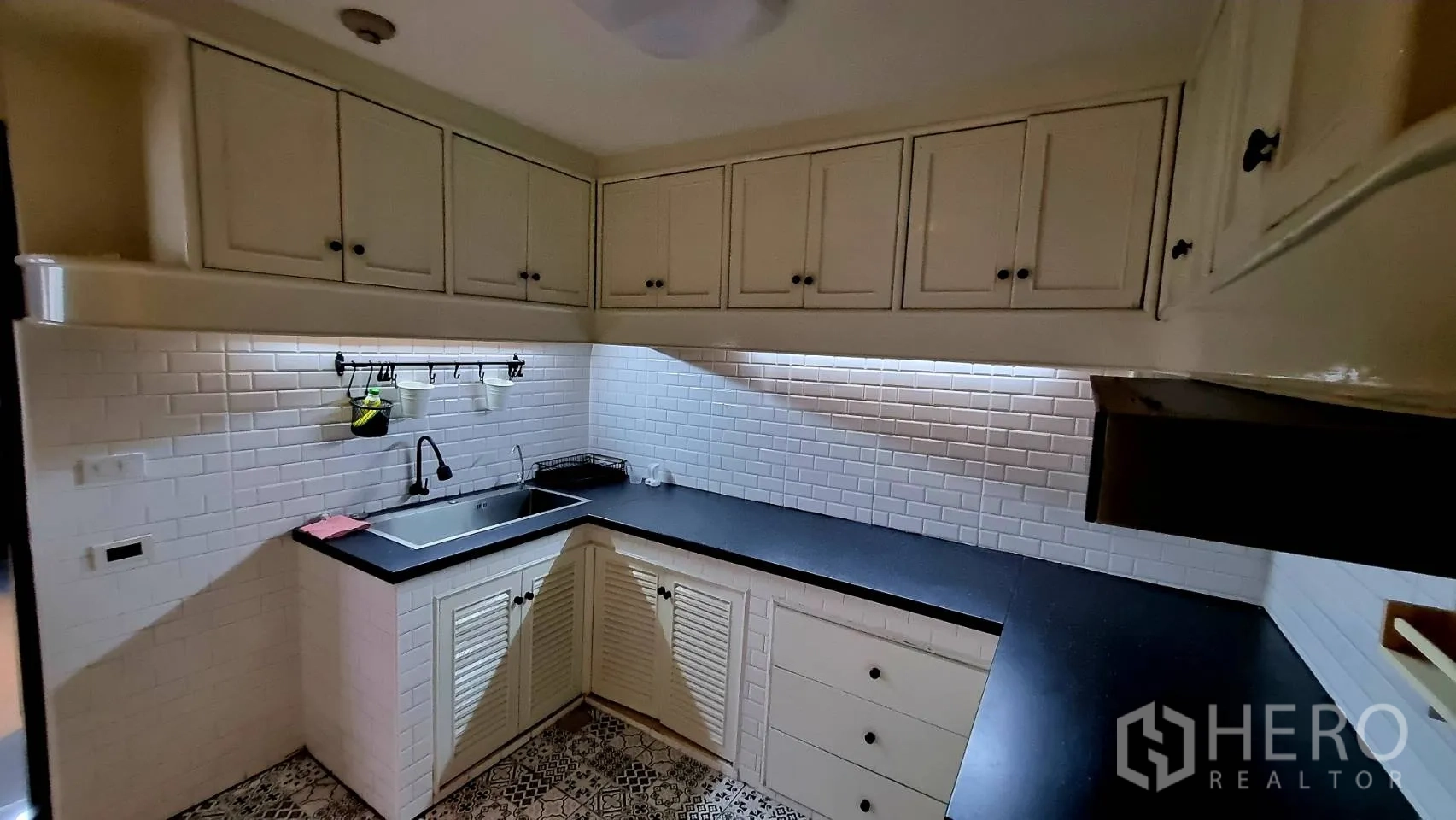 Condominium for rent in Watthana, Bangkok - Kitchen sink area with white cabinets and under-cabinet lighting.