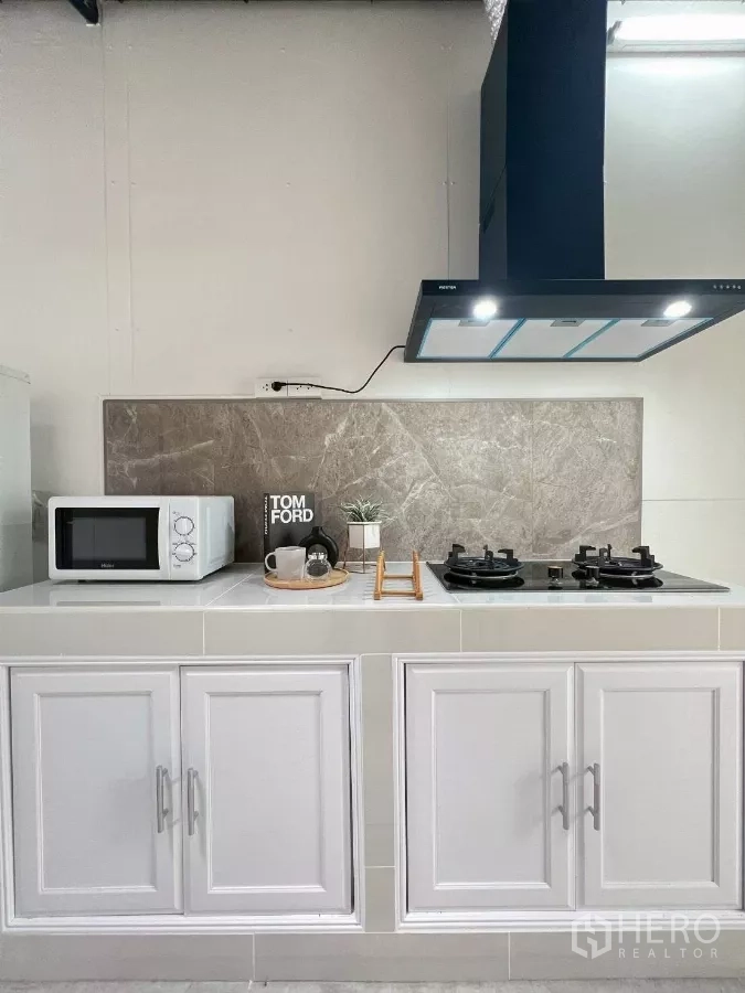 Detached House for rent in Huai Khwang, Bangkok - Full kitchen view with double gas burners, microwave and tiled backsplash.