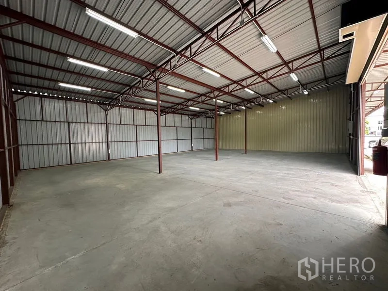 Warehouse for rent in Mueang Nonthaburi, Nonthaburi - Spacious steel-frame warehouse interior with high ceiling, bright strip lighting, and smooth concrete floor.