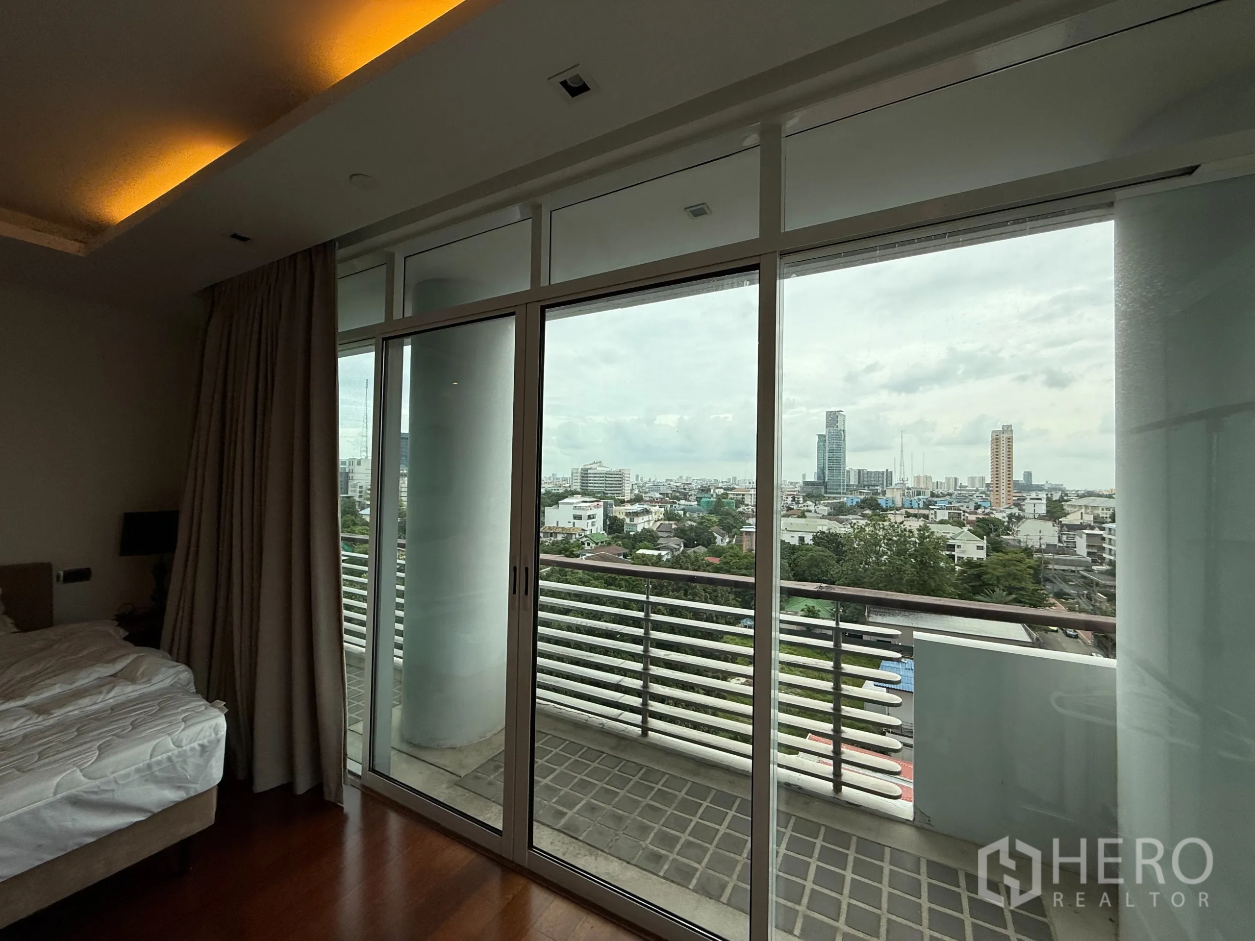 公寓 出租在Phaya Thai, Bangkok - 卧室连接落地玻璃阳台，远眺城市天际线。