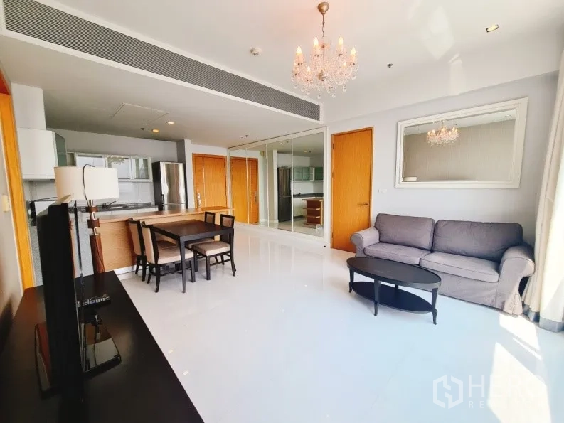Condominium for rent in Khlong Toei, Bangkok - Bright lounge with chandelier, mirrored wall, grey sofa and coffee table.