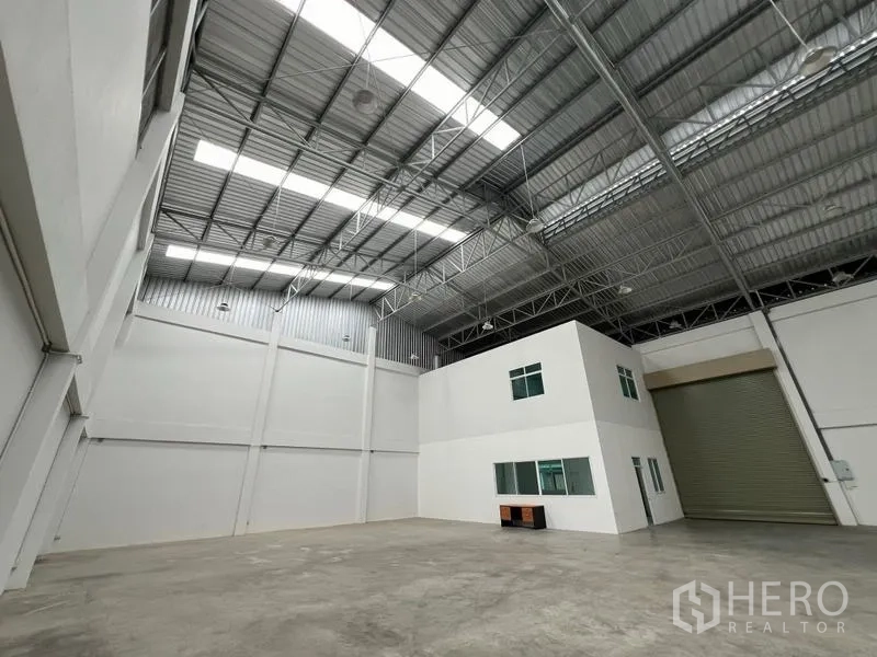 Factory for rent in Phra Samut Chedi, Samut Prakan - Spacious warehouse view showing white internal office block, steel roof and oversized roller door.