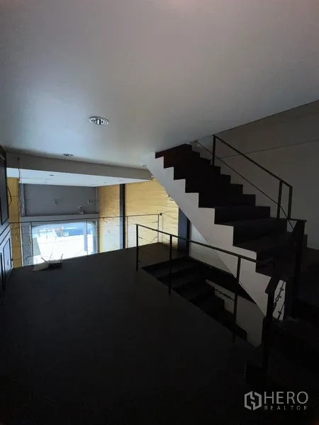 店屋 出租在Watthana, Bangkok - 夹层平台与黑色金属楼梯，俯瞰展厅。