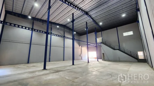 Warehouse for rent in Krathum Baen, Samut Sakhon - Spacious warehouse with insulated high roof, twin roller shutters, and mezzanine stair access for office use.