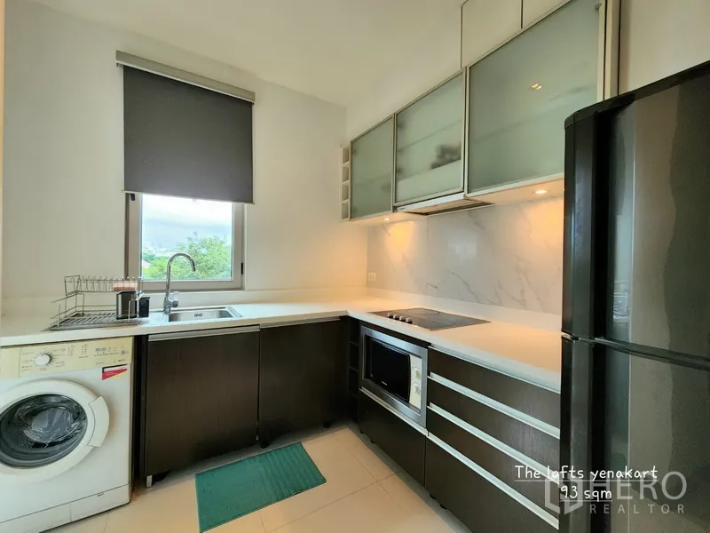 公寓 出租在Yan Nawa, Bangkok - U形现代厨房，白色台面，带窗户、洗衣机、烤箱、灶台与双门冰箱。