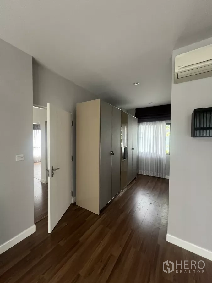 Detached House for sale in Bang Kapi, Bangkok - Walk-through closet area fitted with tall wardrobes and a window at the end.