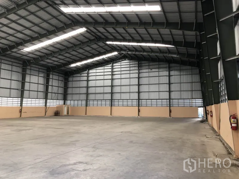 货栈 出租在Pathum Thani - 仓库内部，大跨度无柱空间，高钢梁屋顶、采光带与平整混凝土地面