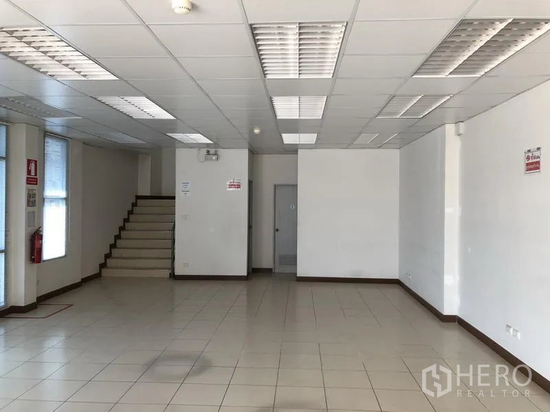 Factory for rent in Bang Sao Thong, Samut Prakan - Bright tiled ground-floor office with drop ceiling lighting and staircase.
