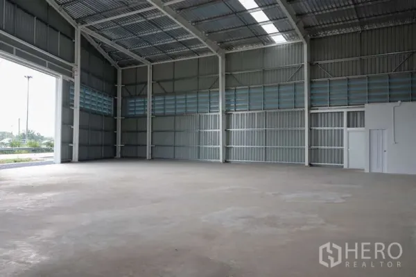 Warehouse for rent in Khlong Luang, Pathum Thani - Spacious warehouse interior with smooth concrete floor and tall entrance for vehicle access.
