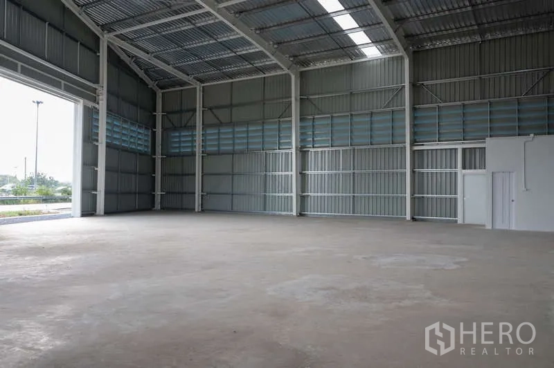 Warehouse for rent in Khlong Luang, Pathum Thani - Spacious warehouse interior with smooth concrete floor and tall entrance for vehicle access.