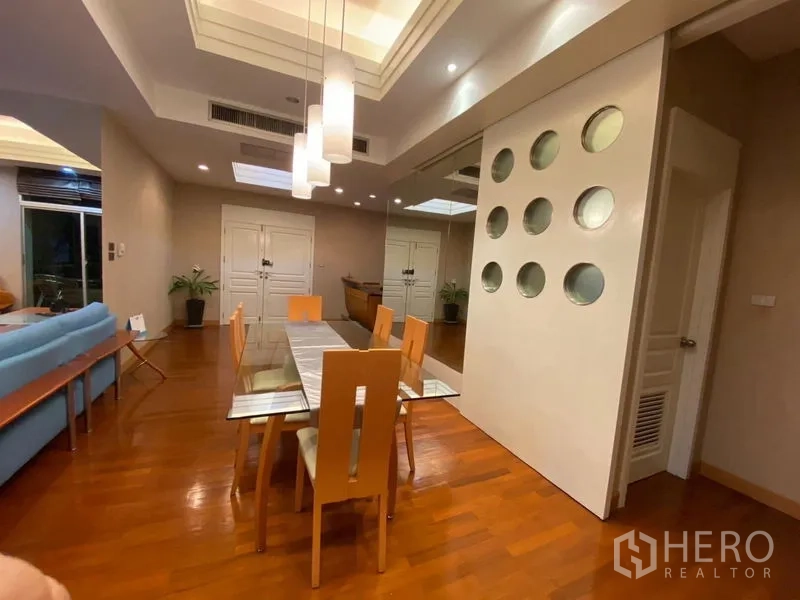 Condominium for rent in Pathum Wan, Bangkok - Dining area with glass table, pendant lights and a modern feature wall with circular cutouts.