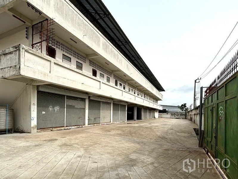 คลังสินค้า ให้เช่าในBang Khun Thian, Bangkok - แถวประตูม้วนช่องโหลด ติดประตูเลื่อนเหล็กสีเขียวและทางรถวิ่ง