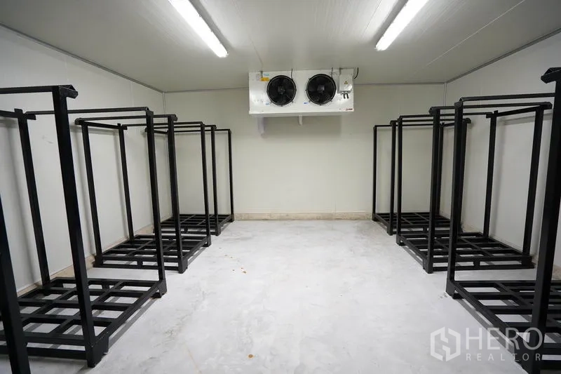 Factory for sale in Khlong Luang, Pathum Thani - Cold storage room with industrial condenser unit and steel shelving racks.