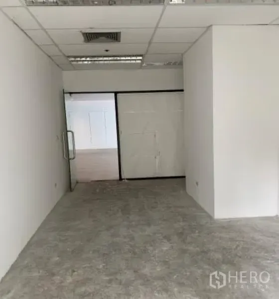零售空间 出租 - 未装修的商铺内部，白色隔墙、格栅吊顶、空调出风口与玻璃门
