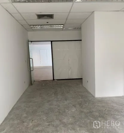 零售空间 出租 - 未装修的商铺内部，白色隔墙、格栅吊顶、空调出风口与玻璃门