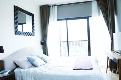 Condominium for rent in Phaya Thai, Bangkok - Primary bedroom with large window, wall mirror above the bed and compact desk area.