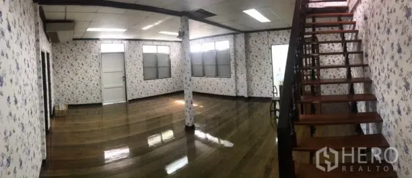 独立式住宅 出租在Sathon, Bangkok - 宽敞客厅，亮光木地板、碎花墙纸与木楼梯。
