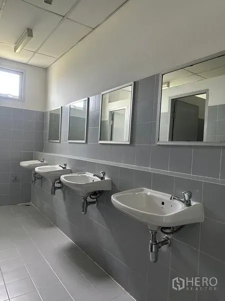 Factory for rent in Pathum Thani - Restroom with three wall-mounted basins, mirrors, and grey tiles.