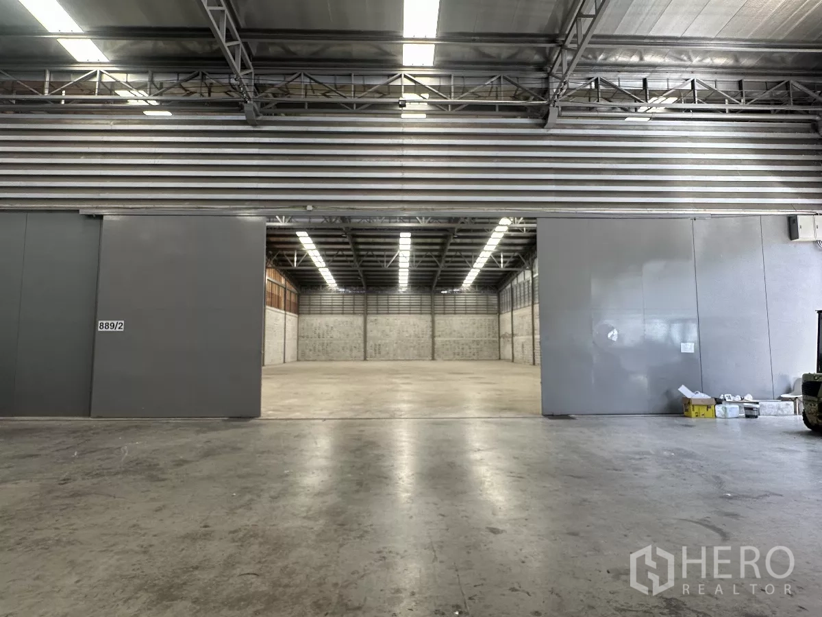 Warehouse for rent in Khlong Toei, Bangkok - Wide sliding metal doors opening to a clear-span warehouse bay with steel roofing.