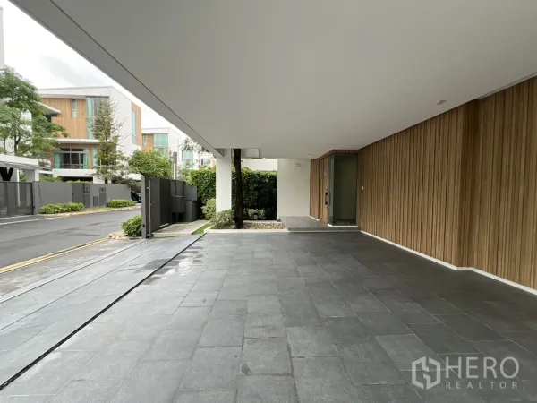 Detached House for rent in Saphan Sung, Bangkok - Covered driveway and entrance with grey tiles and vertical wood cladding.