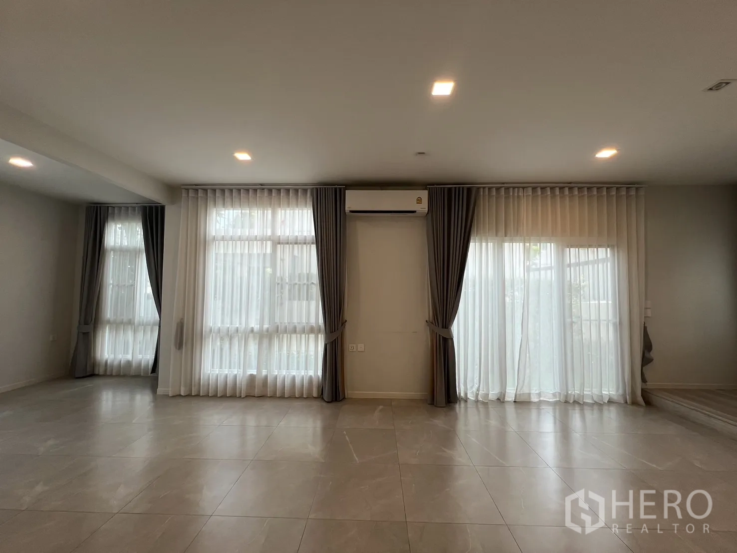 独立式住宅 出租在Prawet, Bangkok - 客厅通透明亮，落地窗、纱帘与大规格地砖。
