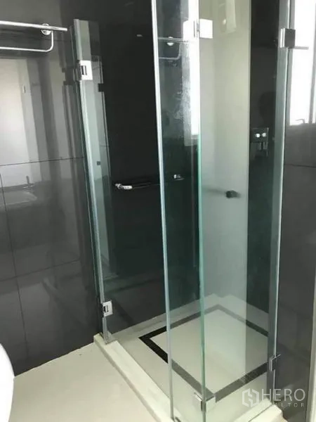 Condominium for rent or sale in Phaya Thai, Bangkok - Frameless glass shower cabin with chrome fittings in a modern bathroom.