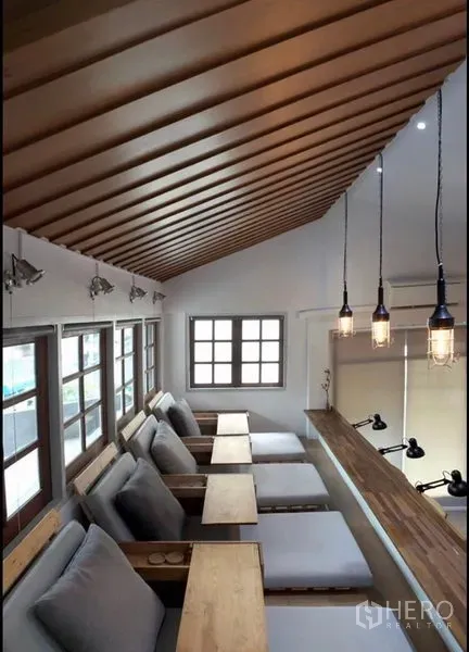 Home Office for rent in Khlong Toei, Bangkok - Mezzanine lounge with reclined seats, side tables and a slatted wood ceiling beside tall windows.