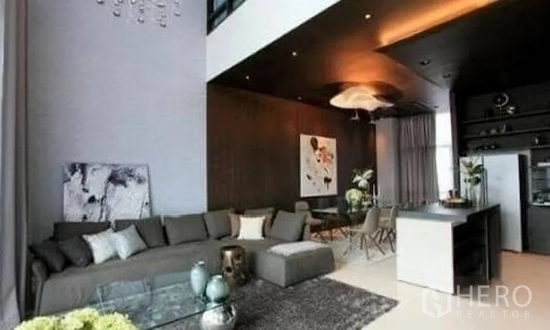 联排别墅 出租在Watthana, Bangkok - 挑高客厅，深色特色墙，大沙发与开放式餐区