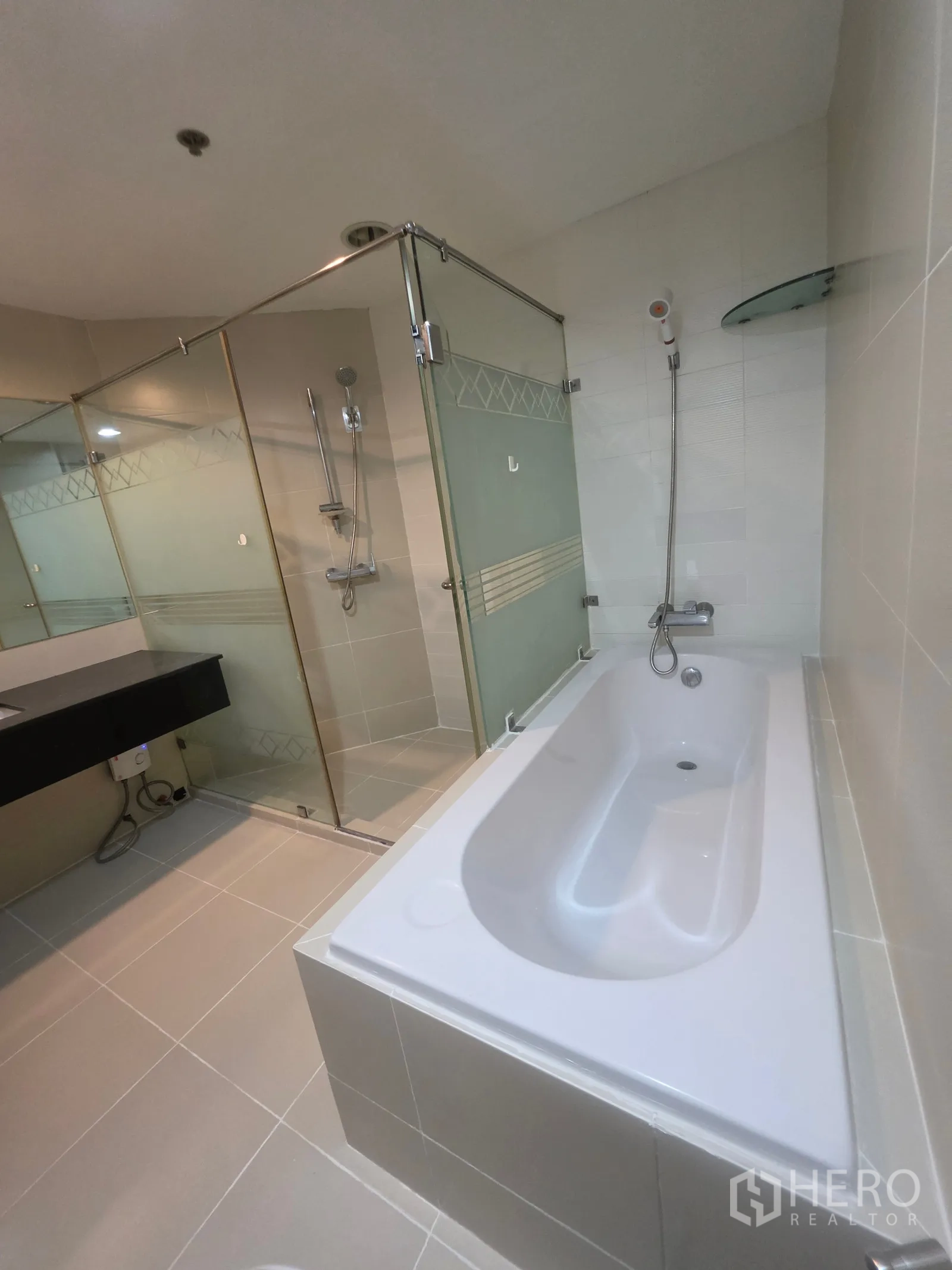 Condominium for rent in Huai Khwang, Bangkok - Spacious bathroom with separate bathtub and glass shower enclosure.