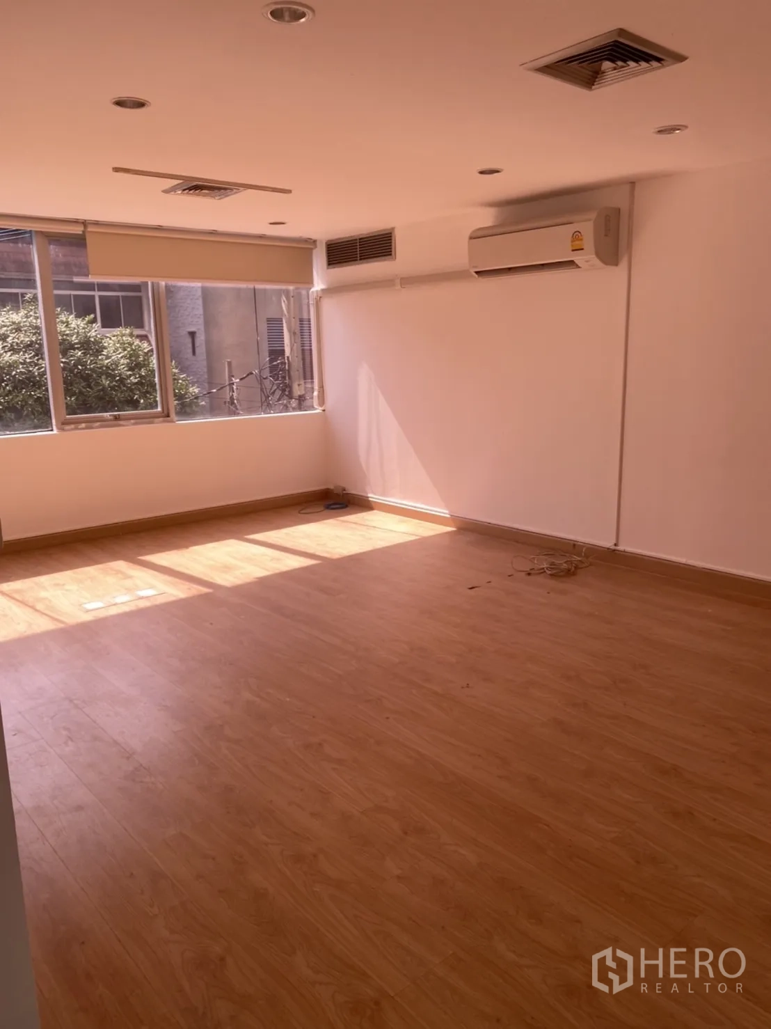 Office Space for rent in Khlong Toei, Bangkok - Private office room with wood‑look flooring, split‑type air conditioner and a wide window.