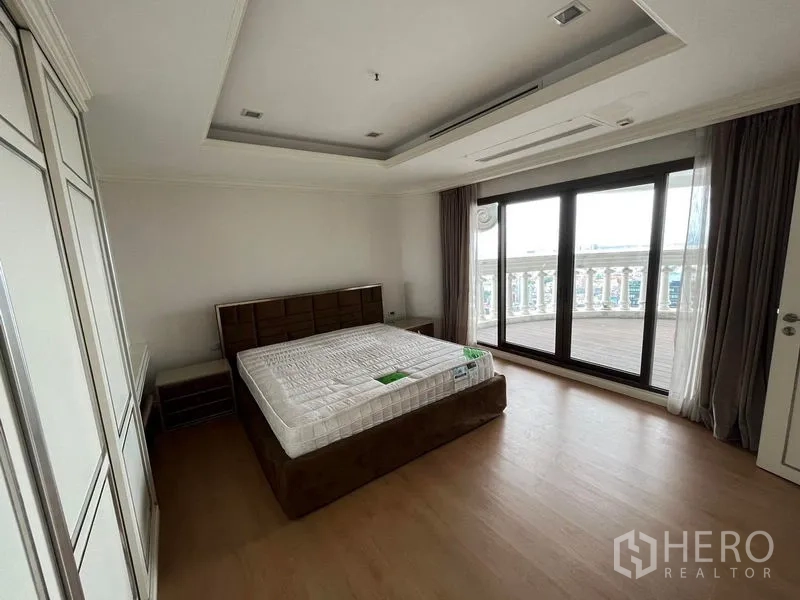 公寓 出售在Bang Rak, Bangkok - 明亮卧室，床、衣柜与推拉门通向环景阳台。