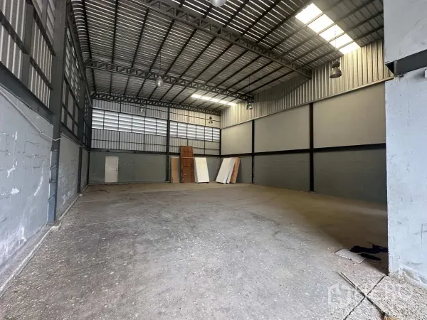 Warehouse for rent or sale in Bang Yai, Nonthaburi - Spacious high-ceiling storage hall with steel trusses, skylights and concrete floor.