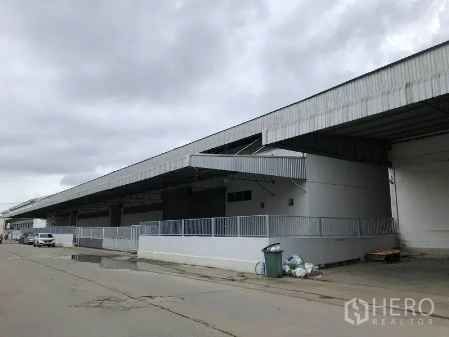 Warehouse for rent in Bang Bo, Samut Prakan - Long warehouse exterior with wide covered loading dock, metal roof canopy and fenced platform.