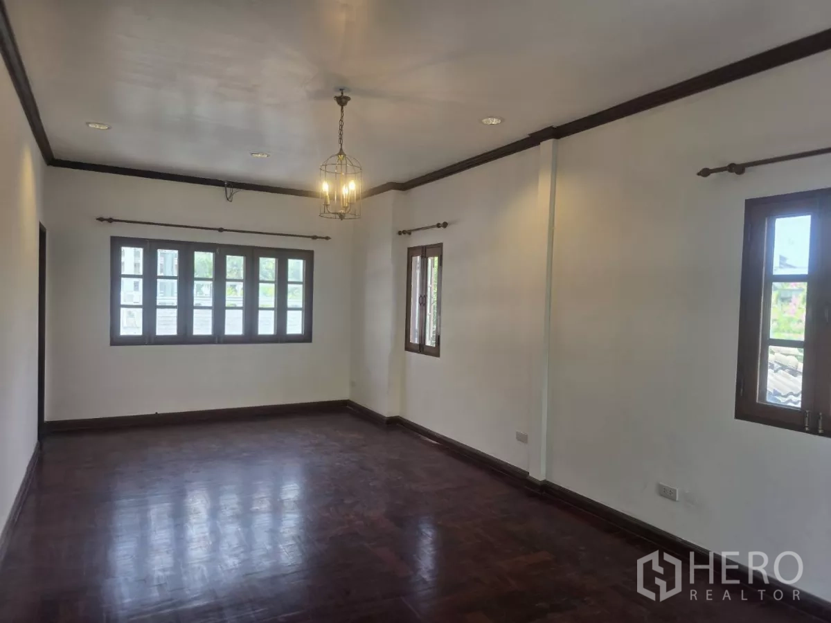 Detached House for rent in Phra Khanong, Bangkok - Second angle of the master bedroom with dual-aspect windows and wood flooring.