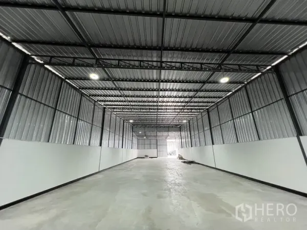 Warehouse for rent in Saphan Sung, Bangkok - Long clear-span storage hall with corrugated metal walls, skylight panels and wide entry at the far end