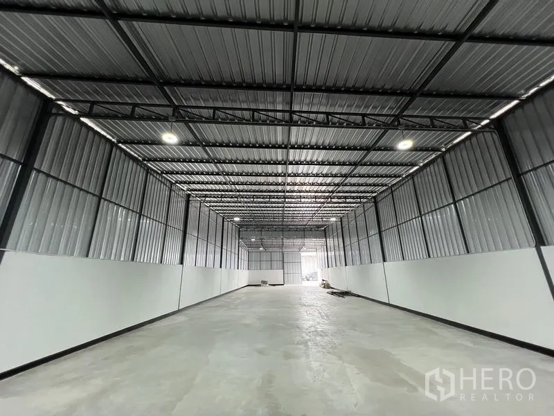 Warehouse for rent in Saphan Sung, Bangkok - Long clear-span storage hall with corrugated metal walls, skylight panels and wide entry at the far end