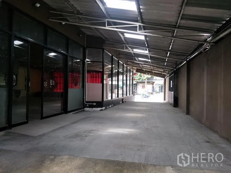 Retail Space for rent in Khlong Toei, Bangkok - Long covered passage with glass storefront walls and concrete driveway for loading or parking.