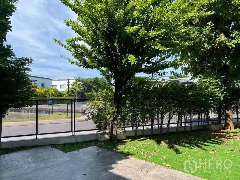 独立式住宅 出租或出售在Bang Phli, Samut Prakan - 前花园树荫成排，修剪整齐的绿篱与道路景观。