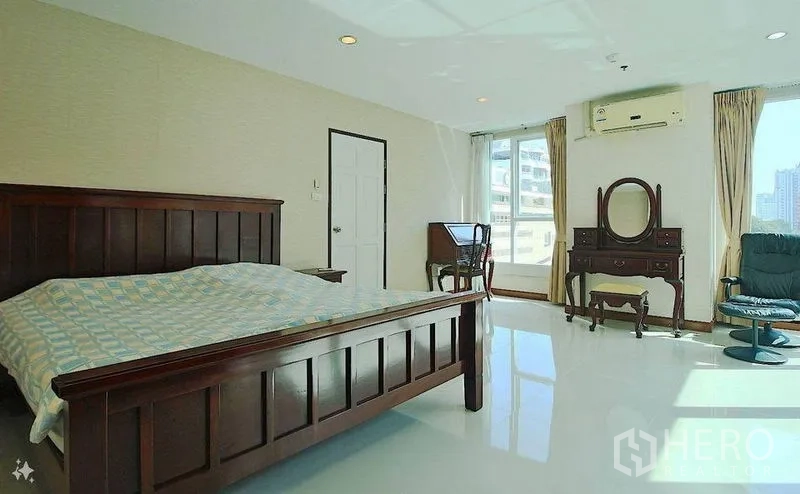 公寓 出售在Watthana, Bangkok - 宽敞主卧，木质家具、书桌，转角窗享城市景观。