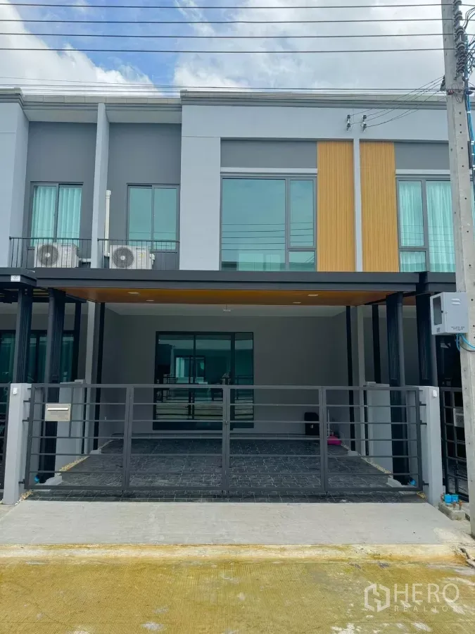 Townhouse for rent in Bang Phli, Samut Prakan - Modern two-storey townhome exterior with gated, covered parking for two cars.