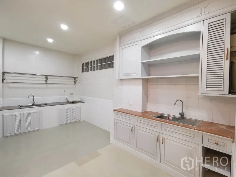 Townhouse for rent or sale in Yan Nawa, Bangkok - Spacious kitchen with white cabinetry, open shelving and double sinks.
